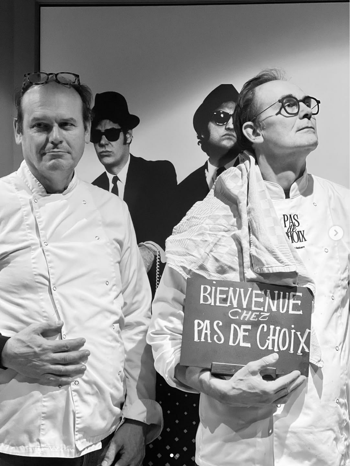 Hans en Guido met een 'Bienvenue chez Pas de Choix'-bord voor een Blues Brothers-poster